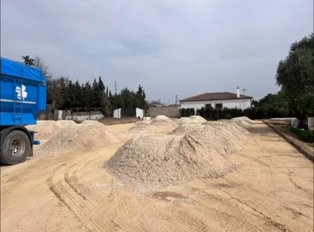Camión de Transportes JJ García junto a montones de árido en obra